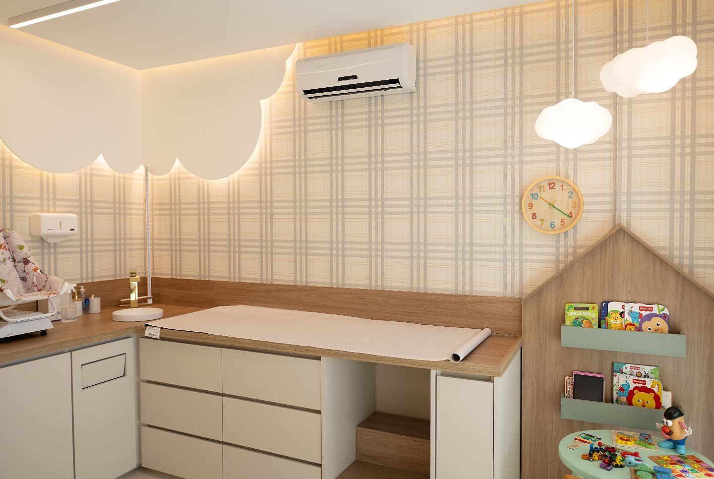 Sala de atendimento do consultório da Dra. Layla Matos, com maca infantil, decoração de nuvens e cantinho de livros e brinquedos